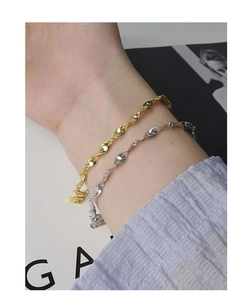 Detailed view of gold and silver Mobius twisted chain bracelets on a woman's wrist