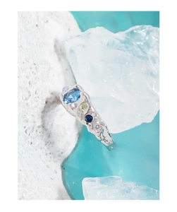 Macro shot of silver ring with blue zircon and moonstone on crystal ice cubes