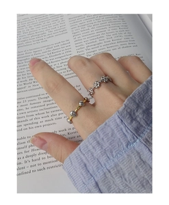 Detailed view of layered S925 silver beaded and gold accent rings on a finger