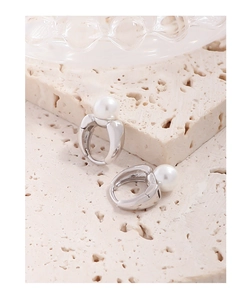 Detailed macro view of S925 silver pearl hoop earrings on a textured stone surface