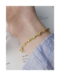 Close-up of golden Mobius twist chain bracelet with lobster clasp on a woman wrist