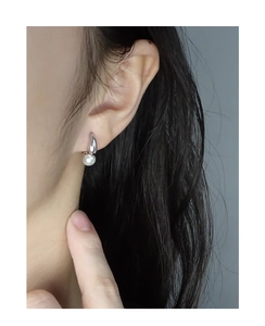 Detail of silver U-shaped earrings with round white pearl charm on female ear