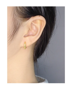 Close-up of minimalist S925 sterling silver golden hoop earrings worn on ear