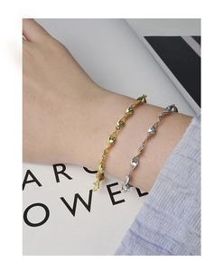 Detail of silver and gold S925 mobius bracelets worn on wrist with elegant wavy design