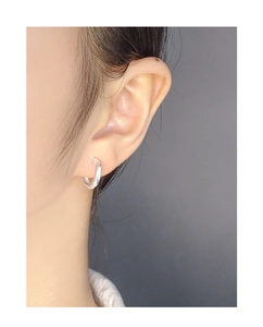 Close-up of minimalist S925 sterling silver hoop earring with irregular polished finish