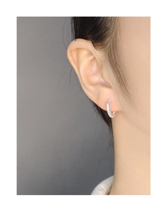 Close-up of minimalist S925 sterling silver hoop earring with irregular polished edge