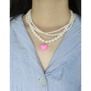 Three-layer pearl necklace featuring a pink enamel heart pendant and gold hardware finish