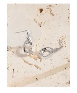 Detailed close-up of irregular S925 sterling silver hoop earrings on a marble surface