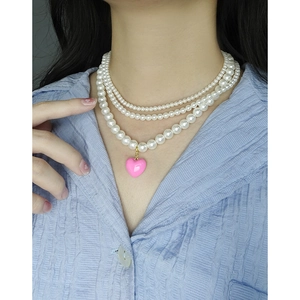 Three-layer pearl necklace with pink heart pendant worn on neck for a sweet layered look