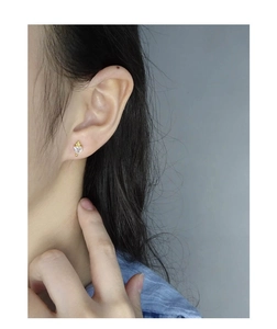 Gros plan d'une boucle d'oreille cœur en zircon et argent s925 doré sur un mannequin