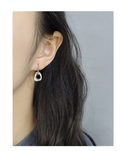Close-up of minimalist S925 sterling silver irregular twisted hoop earrings on ear