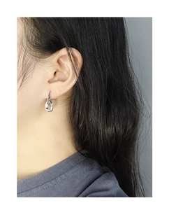 Detail of S925 sterling silver earrings showing the irregular twisted loop on a model
