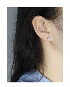 Gros plan d'un clou d'oreille cœur en argent 925 avec zircon porté sur l'oreille