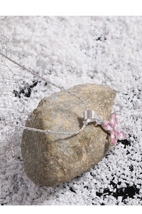 Detail of 925 sterling silver necklace with pink cherry blossom zircon pendant on stone