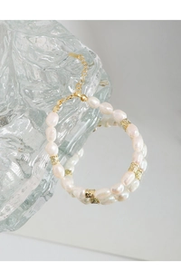 Détail du bracelet en perles baroques avec perles dorées sur surface miroir