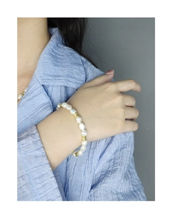 Détail d'un bracelet en perles baroques avec entretoises dorées au poignet d'un mannequin