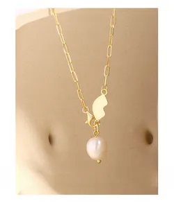 Detailed close-up of golden paperclip chain necklace with a baroque pearl and geometric pendant