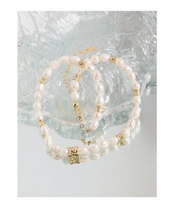 Détail d'un bracelet en perles d'eau douce avec billes dorées sur verre poli