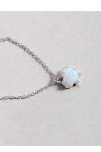 Macro shot of silver heart pendant with iridescent white opal and textured metal detail