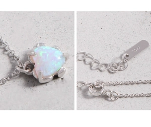 Close-up of S925 sterling silver stamp and heart-shaped opal pendant on a textured chain