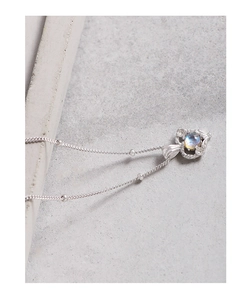 Gros plan du collier coeur en argent S925 avec pierre de lune sur une pierre grise