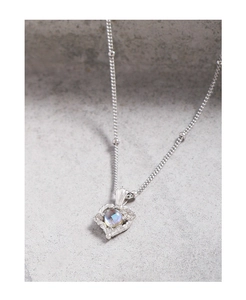 Gros plan du collier coeur en argent S925 avec une pierre de lune centrale lumineuse