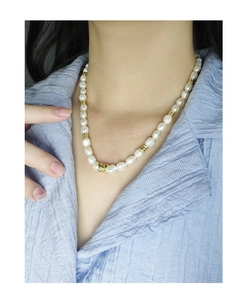 Détail du collier de perles en argent S925 avec entretoises dorées sur haut bleu