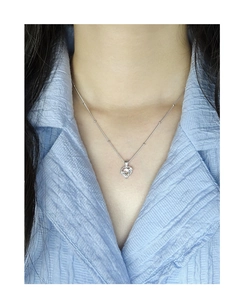 Détail macro du collier cœur en argent S925 avec pierre de lune sur chemise bleue