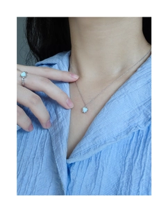 Detail of S925 silver heart opal necklace and ring set worn on a blue textured shirt