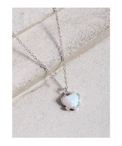 Detailed macro shot of heart opal pendant with silver claw setting on stone background