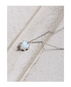 Macro shot of minimalist heart-shaped white opal pendant on a fine silver link chain