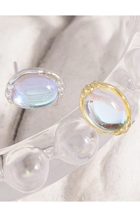 Macro view of silver and gold oval moonstone stud earrings with embossed textures