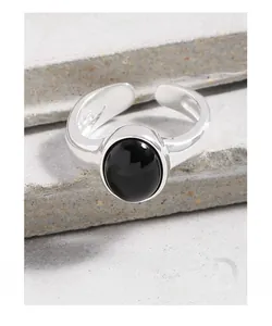 Macro shot of S925 sterling silver ring with oval black onyx stone on gray stone surface