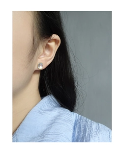 Close-up of minimalist oval moonstone earring with gold beaded trim on model's ear