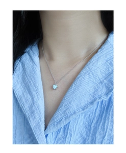 Close-up of S925 silver heart opal necklace worn on neck with textured blue shirt