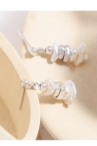 Detailed macro view of S925 silver irregular pearl drop earrings on beige surface