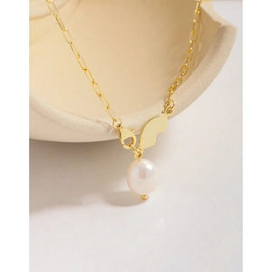 Elegant gold baroque pearl necklace with butterfly pendant on ceramic bowl display