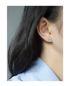 Close-up of minimalist gold S925 silver moonstone stud earring worn by a model
