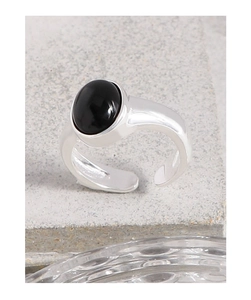 Macro view of minimalist silver ring with oval black onyx and adjustable open band
