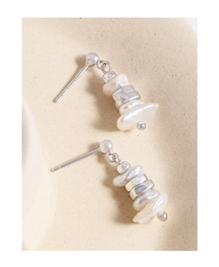 Macro detail of irregular baroque pearls and S925 silver studs on ceramic surface