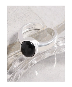 Macro shot of silver ring with oval black onyx gemstone and polished metal finish