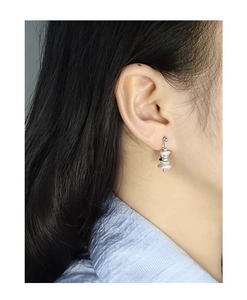 Close-up of minimalist S925 silver earrings with irregular pearls on model's ear