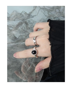Close-up of minimalist S925 silver rings with black agate inlay and textured wavy band