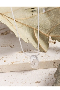 Détail macro du collier en argent S925 avec pendentif galet irrégulier et chaîne fine