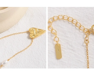 Detail of S925 sterling silver stamp on golden heart necklace with pearl accent