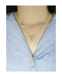 Detail of gold heart pendant with textured finish and single pearl on a delicate chain