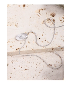 Détail macro d'un collier en argent S925 minimaliste avec pendentif ovale poli irrégulier