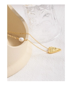 Detailed close-up of golden irregular hammered heart pendant with a white pearl on fine chain