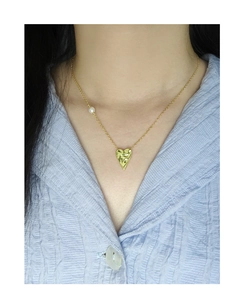 Detailed view of hammered gold heart pendant with elegant pearl on a S925 silver chain