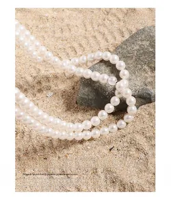 Detail of double-layer white pearl necklace on beach sand and textured rock